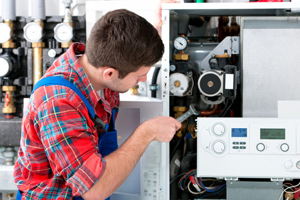 HVAC technician inspecting and repairing boiler controls in Sun City West