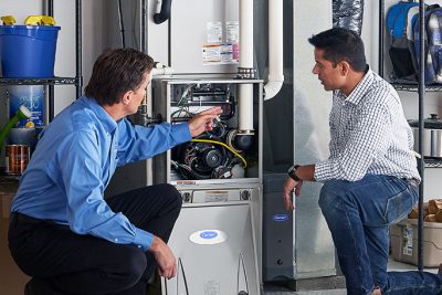 HVAC technician explaining furnace repair and maintenance to a homeowner in Sun City West, AZ