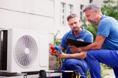 HVAC technicians reviewing an outdoor air conditioning unit in Sun City West, AZ